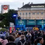 Eine große Menschenmenge versammelt sich vor den Ticketschaltern für die Lange Nacht der Museen" im MuseumsQuartier, Wien, im Hintergrund sind die Veranstaltungsschilder und Gebäude zu sehen.