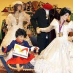 Eine Ausstellung von Schaufensterpuppen in aufwändigen Kostümen, darunter Hochzeitskleider und ein Kinderkostüm, in einem dekorierten Innenraum des Museums.