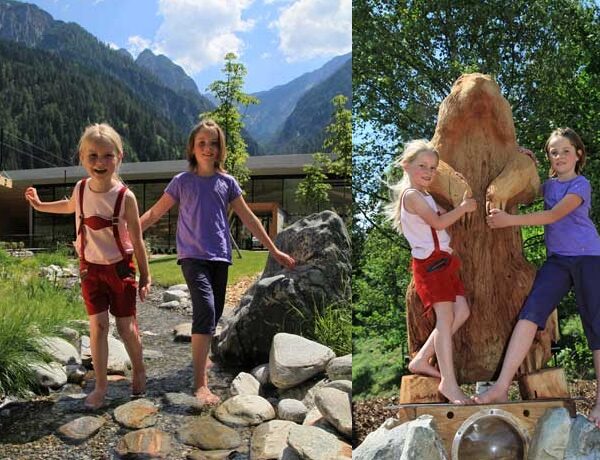 Zwei Mädchen posieren im Freien; auf dem ersten Foto stehen sie auf Felsen neben einem modernen Gebäude und Bergen, und auf dem zweiten halten sie sich an einer großen geschnitzten Tierstatue fest.