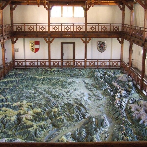 Großes 3D-Geländemodell einer Gebirgslandschaft in einer Holzhalle mit Balkonen und Wappen an den Wänden.