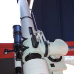 Ein großes weißes Teleskop, das in einer Observatoriumskuppel montiert und auf einen offenen Teil der Kuppel ausgerichtet ist.