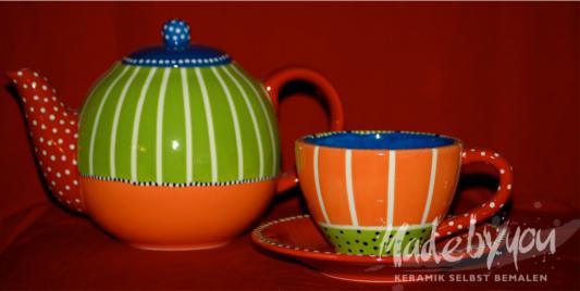 Ein farbenfrohes Teekannen- und Tassenset aus Keramik mit orangefarbenen, grünen, blauen und weißen Mustern vor einem roten Hintergrund.