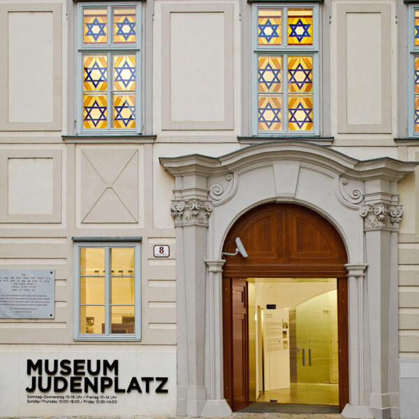 Der Eingang zum Museum Judenplatz mit seinem Rundbogenportal, der Steinfassade und den Glasfenstern mit Davidstern.