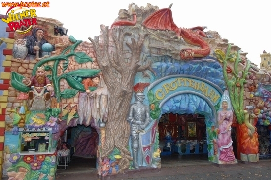 Die farbenfrohe Fassade der Grottenbahn mit Skulpturen aus der Fantasiewelt, darunter ein roter Drache, Ritter und verschiedene Fabelwesen.