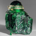 Großes, kunstvoll geschnitztes Smaragdgefäß mit gewölbtem Deckel und goldenen und juwelenbesetzten Akzenten vor einem neutralen Hintergrund.