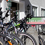 Eine Reihe von Fahrrädern, die vor einem Gebäude mit einem Schild mit der Aufschrift "fun & pro SERVICE CENTER" abgestellt sind.