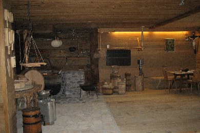 Die rustikale Holzküche ist mit altmodischen Kochgeräten, Fässern, einem Steinofen und Milchkannen ausgestattet und verfügt über schummriges Licht und Holzmöbel.