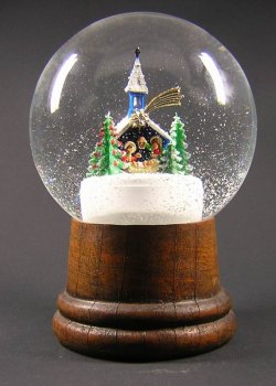 Eine Schneekugel mit Holzsockel und einer Miniaturkirche, Bäumen und Figuren im Inneren, umgeben von Kunstschnee.