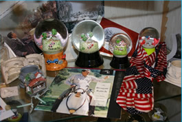 Ein Regal mit Schneekugeln, amerikanischen Flaggen, Figuren, Fotos und einer Schallplatte, die einen Mann in Reiterkleidung zeigt.