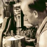 Ein Mann bedient eine mechanische Säge und schneidet in einer Werkstatt sorgfältig ein Muster in einen Holzblock.