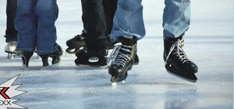 Nahaufnahme der Füße mehrerer Personen, die Schlittschuhe tragen und auf einer Eisbahn Schlittschuh laufen.