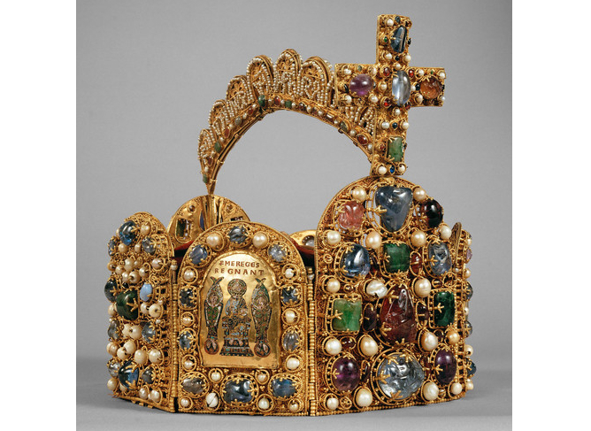Eine mit Edelsteinen, Perlen und einem großen Kreuz geschmückte Goldkrone, die in der Mitte mit einem Bild und Inschriften verziert ist.
