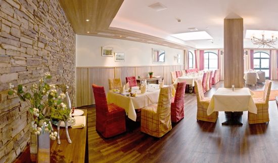 Ein helles, modernes Restaurant mit Stein- und Holzakzenten, weiß gedeckten Tischen und Stühlen mit rot-gelb kariertem Stoff.