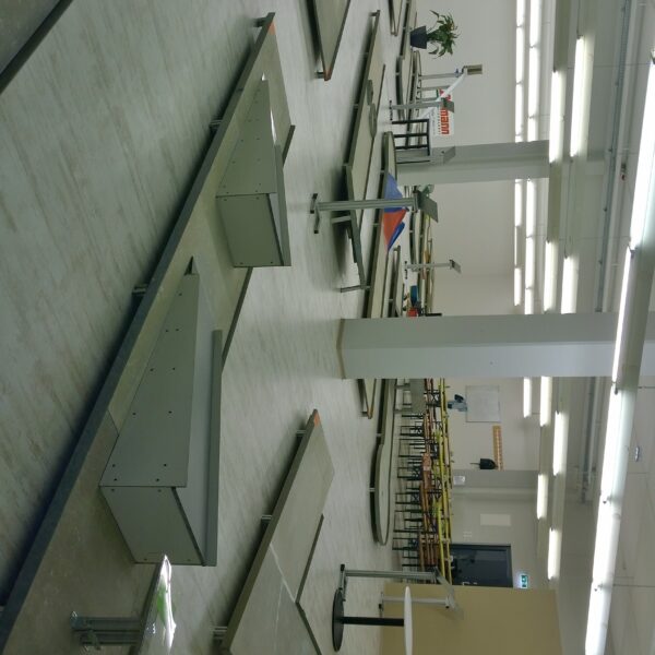 Eine Indoor-Minigolfanlage mit mehreren Bahnen, Hindernissen und Tischen in einem hell erleuchteten Raum mit weißen Wänden und Deckenleuchten.