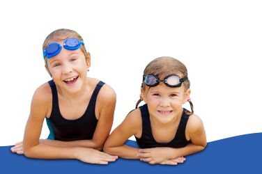 Zwei kleine Kinder mit Schwimmbrillen und schwarzen Badeanzügen lehnen auf einer blauen Fläche und lächeln in die Kamera vor einem weißen Hintergrund.