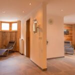 Ein Spa-Ruheraum mit Holzwänden, Liegestühlen, einem kleinen Holztisch und sanfter Beleuchtung schafft eine ruhige Atmosphäre.