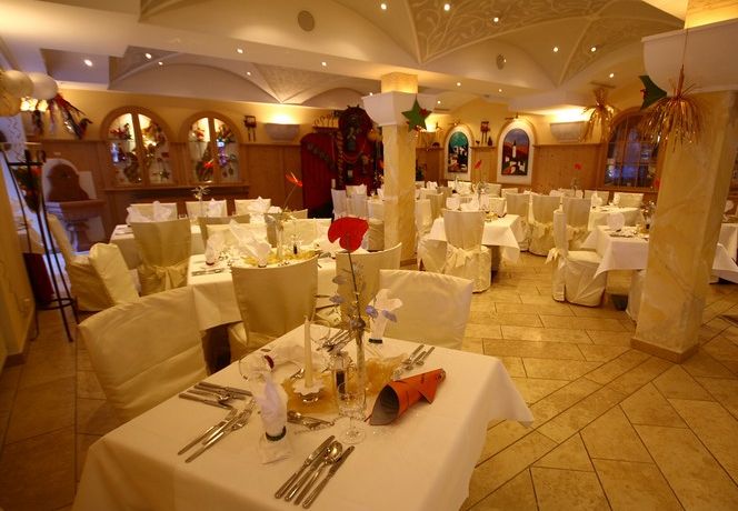 Eleganter Speisesaal eines Restaurants mit ordentlich gedeckten Tischen, weißen Tischdecken und dekorativen Elementen an Wänden und Tischen, bereit für Gäste.