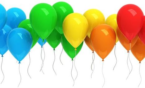 Eine Gruppe aufgeblasener Ballons in den Farben Blau, Grün, Gelb und Orange, die vor einem weißen Hintergrund schweben und an denen Schnüre herunterhängen.