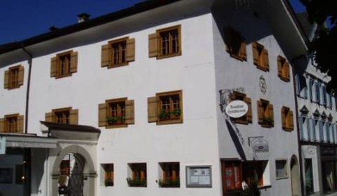 Ein weißes dreistöckiges Gebäude mit hölzernen Fensterläden und Blumenkästen, am Eingang ein Schild mit der Aufschrift „Bauhof Garmisch“.
