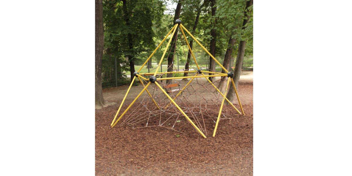 Ein gelbes Metallklettergerüst mit Seilnetz steht auf Raufaserboden in einem von Bäumen umgebenen Park.