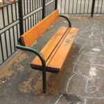 Eine hölzerne Parkbank auf einer gepflasterten Fläche neben einem mit Kreide gezeichneten Himmelfahrtskommando.