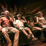 Vier Personen mit 3D-Brillen sitzen in den Sitzen des Bewegungssimulators und erleben eine immersive Fahrt mit dynamischen Lichteffekten und verschwommenen Bewegungen im Hintergrund.