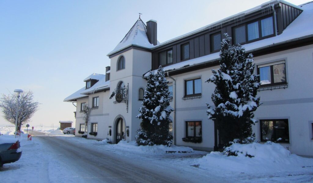 Ein großes, dreistöckiges Gebäude mit schneebedeckten Bäumen und Boden, das an einem klaren Wintertag an einer Straße steht.