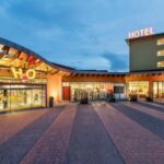 Modernes Hotel in der Abenddämmerung, mit großem "HOTEL"-Schild am Gebäude, gläsernem Eingang und gut beleuchteten Gehwegen.