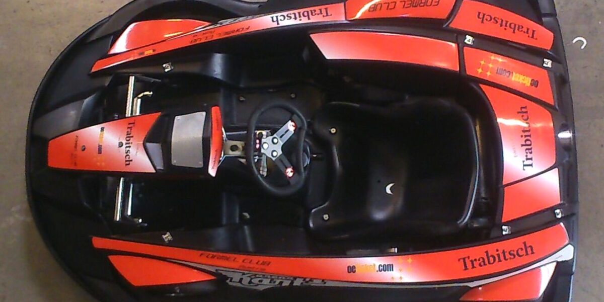 Draufsicht auf ein rot-schwarzes Gokart mit "Trabitsch"- und "FORMEL CLUB"-Schriftzug, das den Sitz, das Lenkrad und die Schutzverkleidung zeigt.