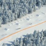 Luftaufnahme eines schneebedeckten Terrainparks in einem Wald mit verschiedenen Rampen, Schienen und Hindernissen für den Wintersport.