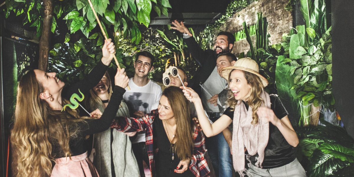 Eine Gruppe von Menschen posiert spielerisch unter einem „JUNGLE“-Schild im Schokoladenmuseum Wien, umgeben von künstlichen Pflanzen und Dekorationen zum Thema Dschungel.