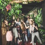 Eine Gruppe von Menschen posiert spielerisch unter einem „JUNGLE“-Schild im Schokoladenmuseum Wien, umgeben von künstlichen Pflanzen und Dekorationen zum Thema Dschungel.