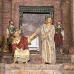 Ein historisches Diorama zeigt eine sitzende Figur in einer Robe, die auf einen stehenden Mann in einer Robe gestikuliert, während im Hintergrund zwei gepanzerte Wachen zuschauen.