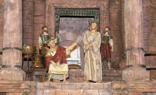 Ein historisches Diorama zeigt eine sitzende Figur in einer Robe, die auf einen stehenden Mann in einer Robe gestikuliert, während im Hintergrund zwei gepanzerte Wachen zuschauen.