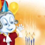 Eine Zeichentrickfigur in einem roten Mantel und einem Partyhut winkt bei brennenden Geburtstagskerzen, mit bunten Luftballons und einem eingepackten Geschenk im Hintergrund.