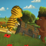 Ein animierter Tiger und ein Bär tragen eine große Truhe neben einem Bach in einer grasbewachsenen, blumenreichen Landschaft mit Bäumen im Hintergrund.