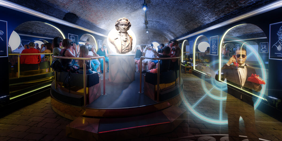 Eine Gruppe von Menschen sitzt um eine große Beethoven-Büste in einem gewölbten, schwach beleuchteten Raum mit leuchtenden digitalen Effekten und Porträts an den Wänden.