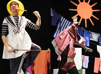 Zwei Darsteller auf der Bühne: einer im Matrosenoutfit und mit gelbem Hut, der einen Stock hält, der andere teilweise mit Kleidung bedeckt, mit einer Sonne und hängender Wäsche im Hintergrund.