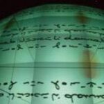 Ein großer, beleuchteter grüner Globus zeigt horizontale Textzeilen, die in einer unbekannten Schrift oder einem unbekannten Code über seine Oberfläche geschrieben sind.