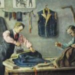 Zwei Schneiderinnen arbeiten in einer Werkstatt. Die eine bügelt auf einem Tisch Stoff, während die andere ein Kleidungsstück von Hand näht. Werkzeuge, Kleidung und Schnittmuster hängen an der Wand hinter ihnen.