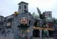 Eine dunkle, schlossähnliche Vergnügungsparkattraktion mit steinähnlichen Wänden, gruseligen Dekorationen und bunten Lichtern an der Außenseite.