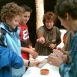 Eine Gruppe von Kindern und ein Erwachsener versammeln sich um einen Tisch und beschäftigen sich mit Ton.