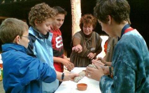 Eine Gruppe von Kindern und ein Erwachsener versammeln sich um einen Tisch und beschäftigen sich mit Ton.