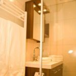 Kleines Badezimmer mit einem Handtuchhalter, weißen Handtüchern, einem Waschbecken mit modernem Wasserhahn und einem Wandspiegelschrank.