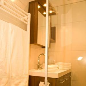 Kleines Badezimmer mit einem Handtuchhalter, weißen Handtüchern, einem Waschbecken mit modernem Wasserhahn und einem Wandspiegelschrank.