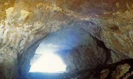 Blick aus dem Inneren einer Felsenhöhle auf einen hellen, sonnenbeschienenen Eingang.