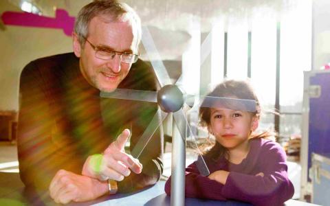 Ein Mann und ein Mädchen schauen auf eine Windmühle.