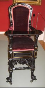 Verschnörkelter antiker Holzstuhl mit hoher Rückenlehne, rotem Samtbezug, detaillierten Schnitzereien, schwarzer Lackierung und Krallenfüßen, ausgestellt in einer Museumsumgebung.