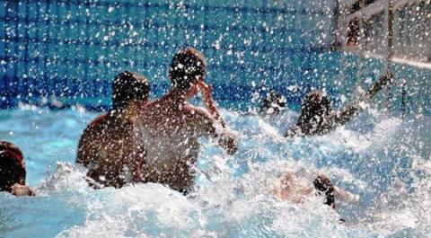 Mehrere Personen schwimmen und spielen in einem Pool, wobei das Wasser um sie herum spritzt.