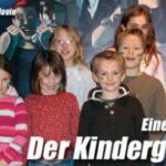 Eine Gruppe lächelnder Kinder posiert vor einem Filmplakat mit deutschem Text, das für eine lustige Geburtstagsparty im Kino wirbt.